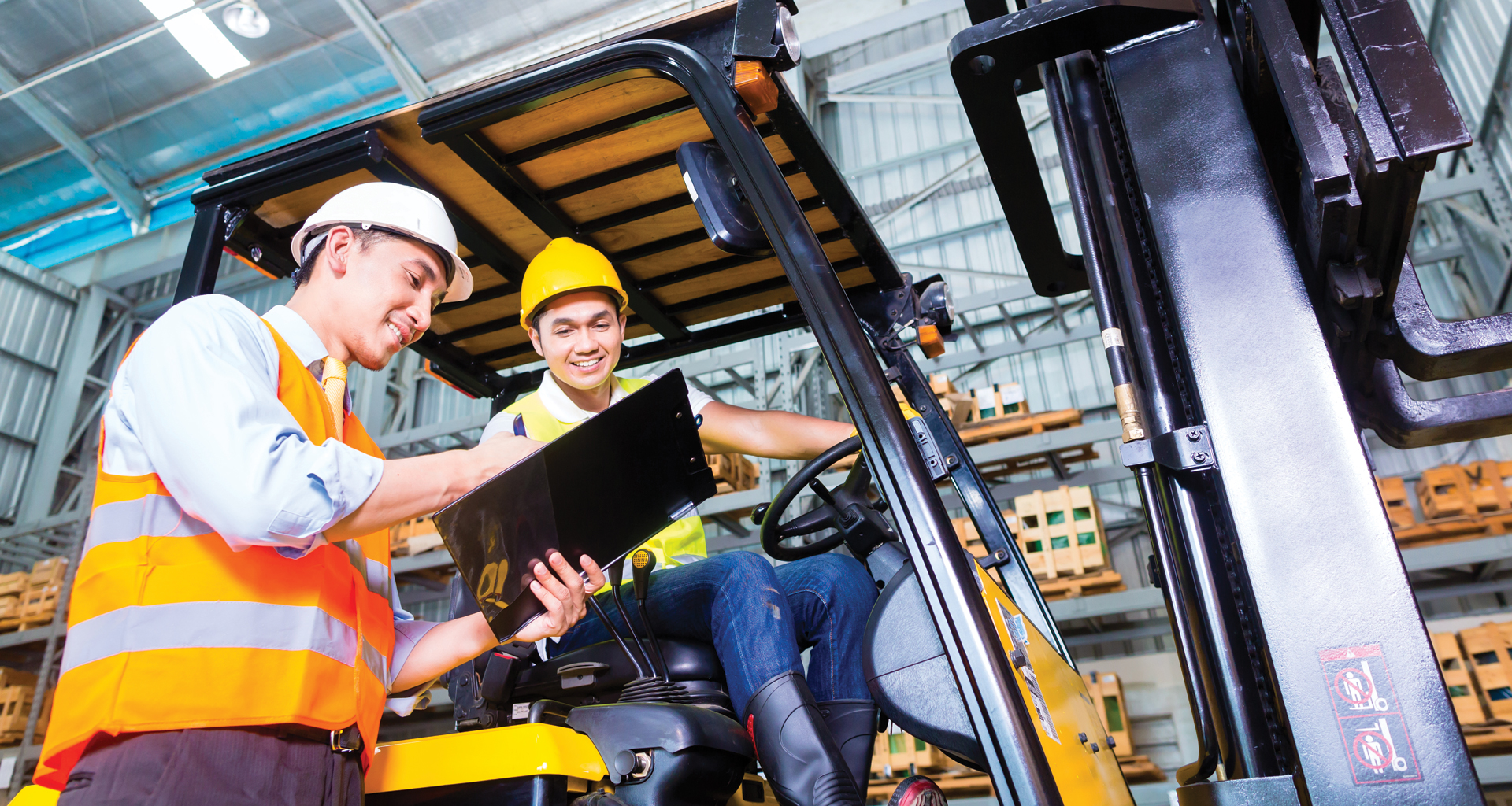 Blue collar workers with safety vests discussing documents on a clipboard.