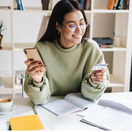 Young lady reads social security card while typing it in to her smartphone.