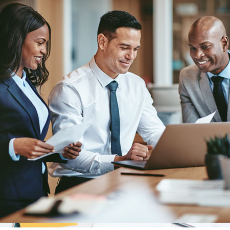 Young, diverse businessmen and women discuss information in front of a computer screen.