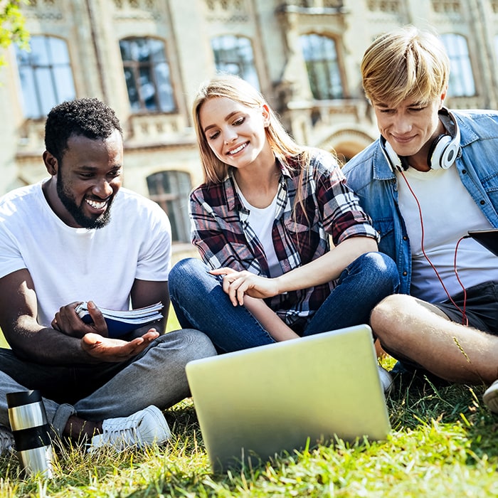 College students on lawn using laptop