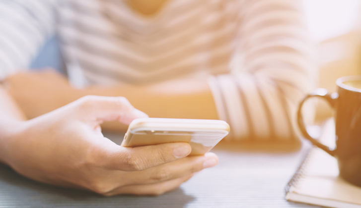 A hand grasping a smartphone.