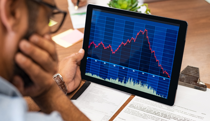 Gentleman with glasses looking at financial charts on a tablet.