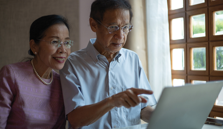 An older couple examines a computer screen.