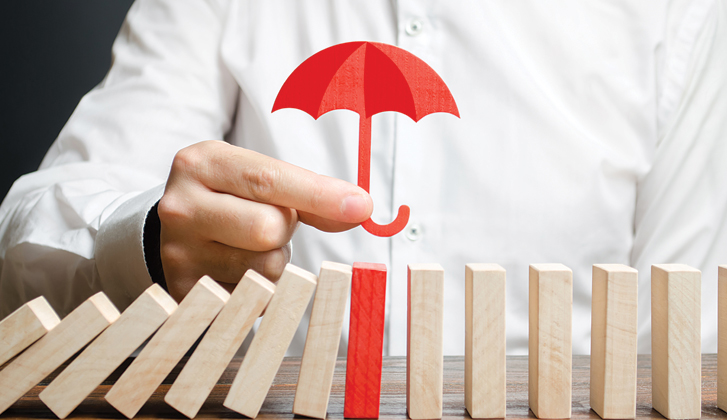 Gentleman holds small red wooden umbrella over row of wooden blocks. The one directly under the umbrella is also painted red.