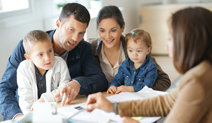 Young couple with two children on their laps reviews documents