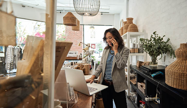 Female Business Owner in her store reviewing a Laptop