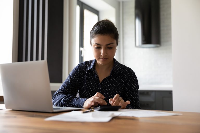 teenage girl sitting at a table with her laptop and calculator