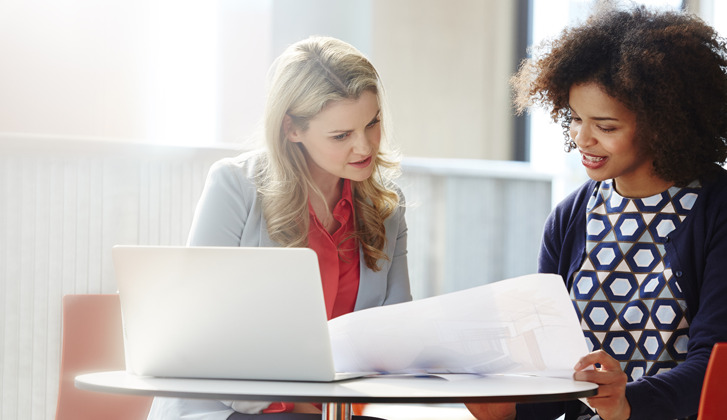 Two women read over documents at a desk