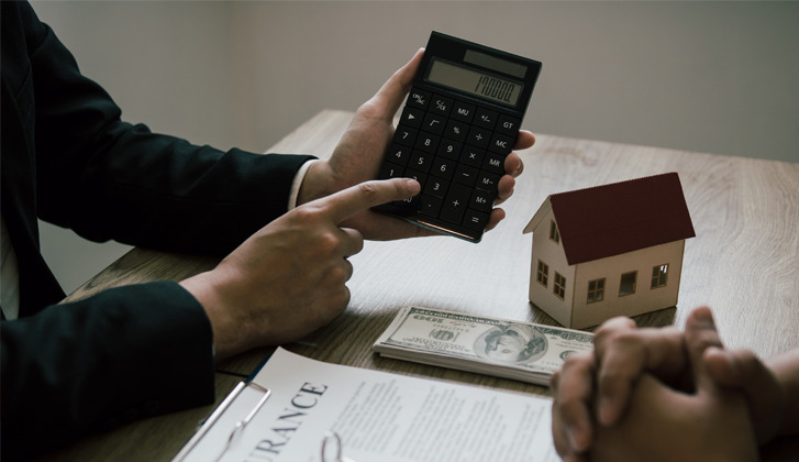 hands holding a calculator, pointing. another set of hands intertwined. Discussion over documents.