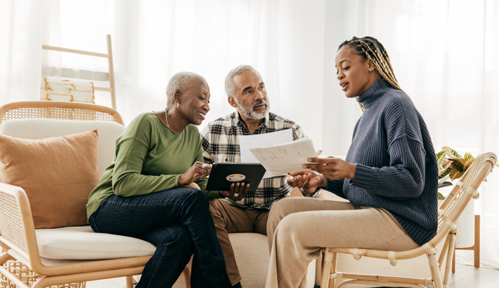 Family discussing documents while sitting in the living room together.