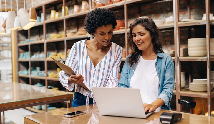 business owner having a conversation while standing over a laptop